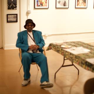Blue Suited Man Sitting on Hardwood Chair in Art Gallery