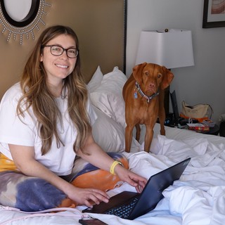 Woman and Dog Working from Bed
