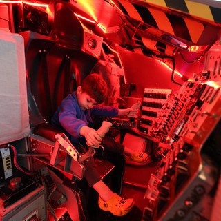 Young Visitor Explores Space Shuttle Cockpit Simulator
