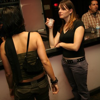 Two Women Conversing at a Dimly Lit Bar
