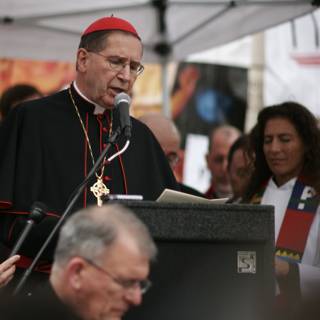 Red-Hatted Bishop Addresses Crowd at Podium