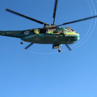 Green Helicopter Soaring High in the Blue Sky