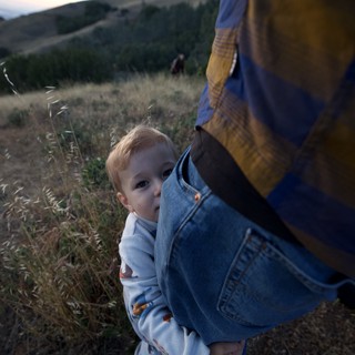 Toddler Clings to Parent's Leg at Dusk