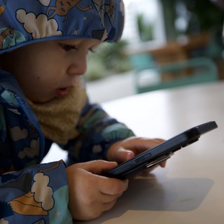 Young Child Engaged with Smartphone at Restaurant