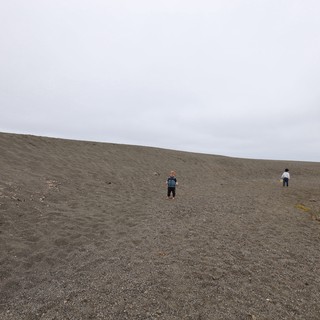 Children Exploring a Vast Dark Sand Beach