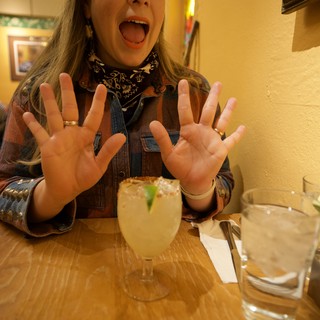 Enthusiastic Woman Celebrating with Margarita at Restaurant