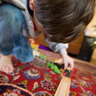 Child Playing with Wooden Train Set on Ornate Carpet
