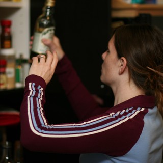 Woman Examining Bottle in Dimly Lit Kitchen