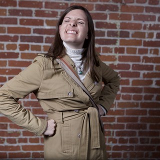 Playful Woman Strikes Pose Against Urban Brick Wall