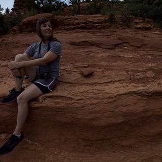 Woman Photographer Resting on Red Rock Formation in Sedona