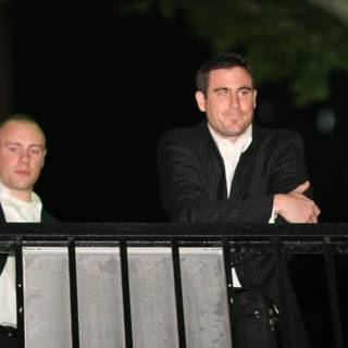 Two Men in Formal Wear Standing on Balcony