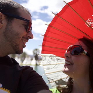 Couple Shares a Smile Under Red Parasol at Coachella