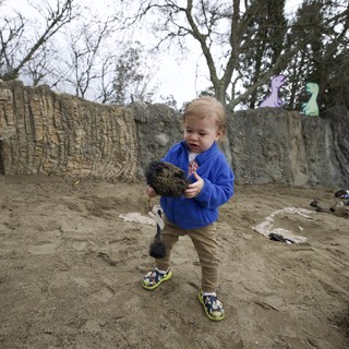Toddler Exploring Sandy Play Area with Shovel