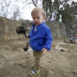 Toddler with Brush at Sandy Play Area