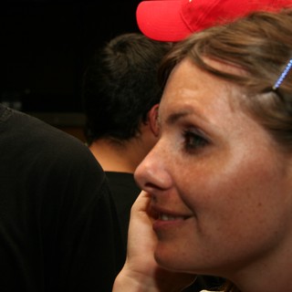 Woman in Red Cap Smiling at Indoor Gathering