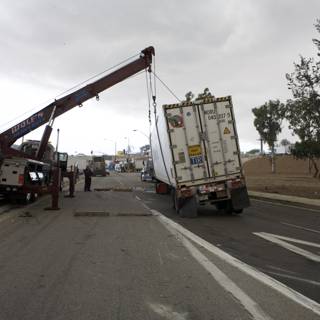 Crane lifting overturned truck off street
