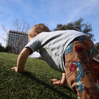 Child Playing on Grass in Urban Park Setting
