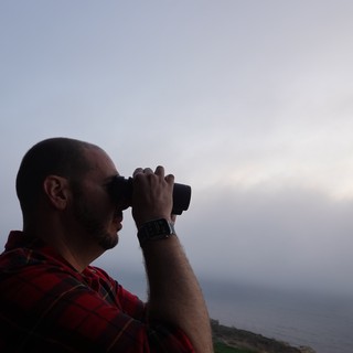 Man with Binoculars Observing Coastal Landscape