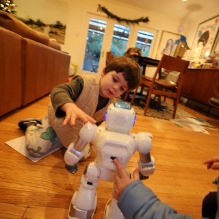 Child Playing with White Robotic Toy Dog at Home
