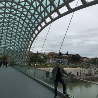 Man stands in awe of stunning glass architecture on Tbilisi bridge
