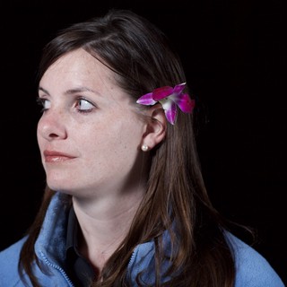 Woman with Orchid in Hair Against Dark Background