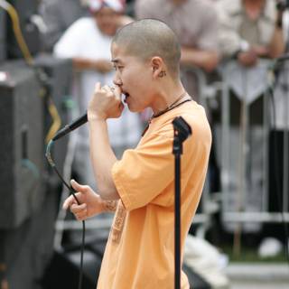 Man with Orange Shirt Speaking into Microphone