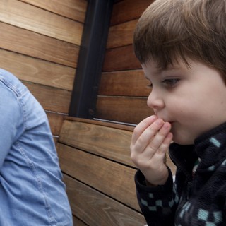 Young Boy Whispering Secret to Friend by Wooden Wall