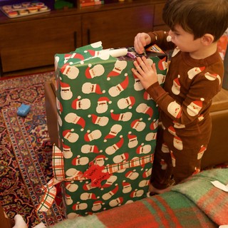 Christmas Morning: Child Unwrapping Santa-Themed Present