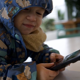 Young Child with Phone at Outdoor Dining Area