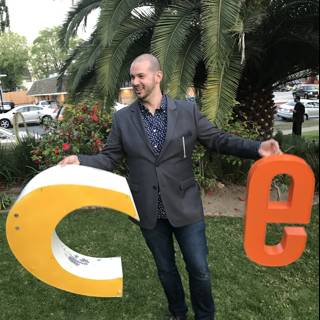 Man Standing Next to Large C Sign