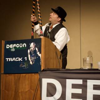 Microphone in Hand Caption: A man holds a microphone while addressing the crowd at Defcon 18.