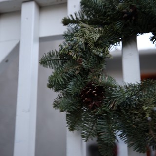 Evergreen Garland on White Porch Railing with Pine Cone
