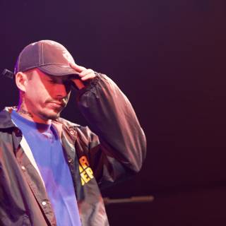 Man in Baseball Cap and Jacket Performing on Stage