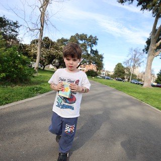 Young Boy Walking Through Park with Snack