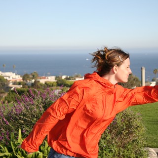 Woman in Orange Jacket Embracing Ocean Breeze