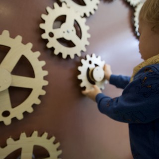 Child Playing with Wooden Gear Wall Installation