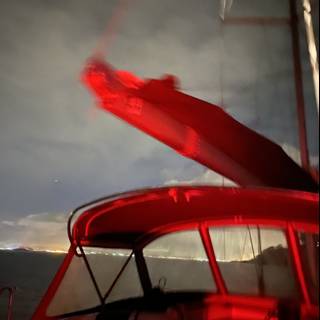 Red Light Illuminates Sailboat in the Bay