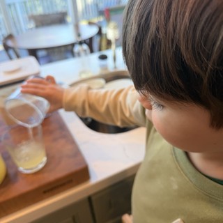 Young Child Drawing and Drinking at Home Table
