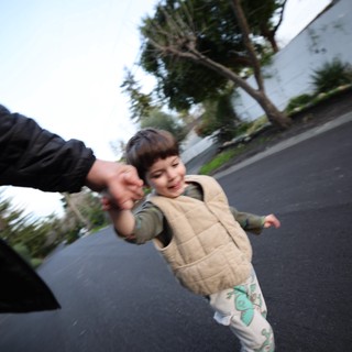 Child Walking Hand-in-Hand on Suburban Street