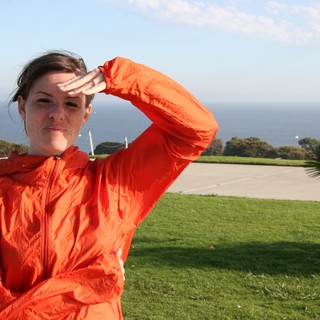 Woman in Orange Jacket Shielding Eyes by Ocean