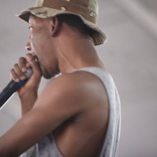Sam R performs with a microphone and a hat at Coachella 2011