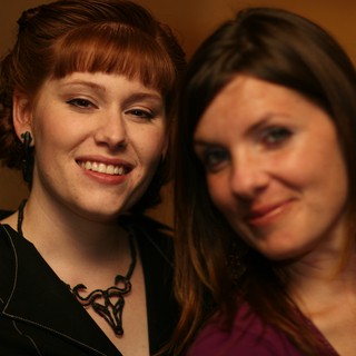 Two Smiling Women at an Indoor Social Gathering