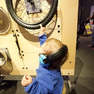 Young Child Explores Interactive Bicycle Wheel Exhibit