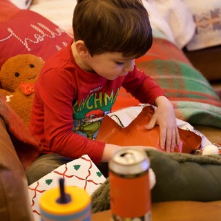 Young Boy Opening Christmas Presents in Cozy Living Room