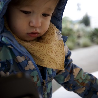 Young Child in Patterned Raincoat with Smiley Bib