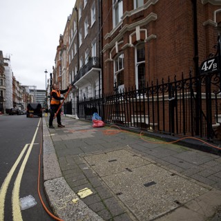 Utility Worker Pressure Washing London Street Sidewalk