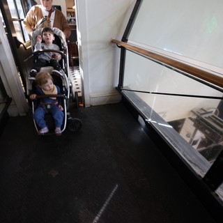 Parent Navigating Double Stroller Through Historic Building Hallway