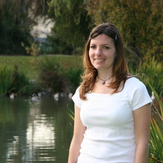 Young Woman Smiling by a Tranquil Park Pond