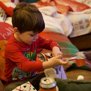 Young Child Opening Christmas Presents on Cozy Couch