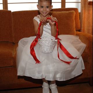 Little girl in a white dress with a basket sitting on a couch